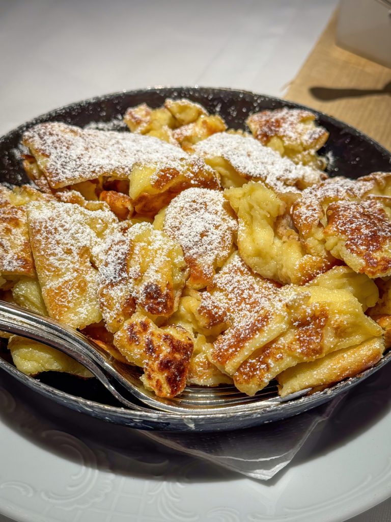 Frisch gebratener Kaiserschmarrn in einer Pfanne mit Puderzucker.