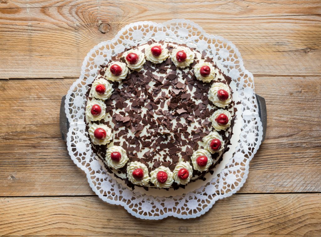 Ganze Schwarzwälder Kirschtorte mit Sahnetuffs, Kirschen und Schokoraspeln von oben.