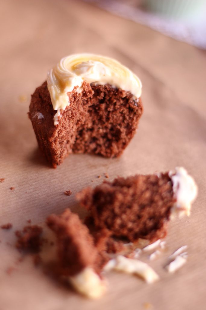 Halbierter Schokocupcake mit Resten von Frischkäsecreme auf Backpapier.