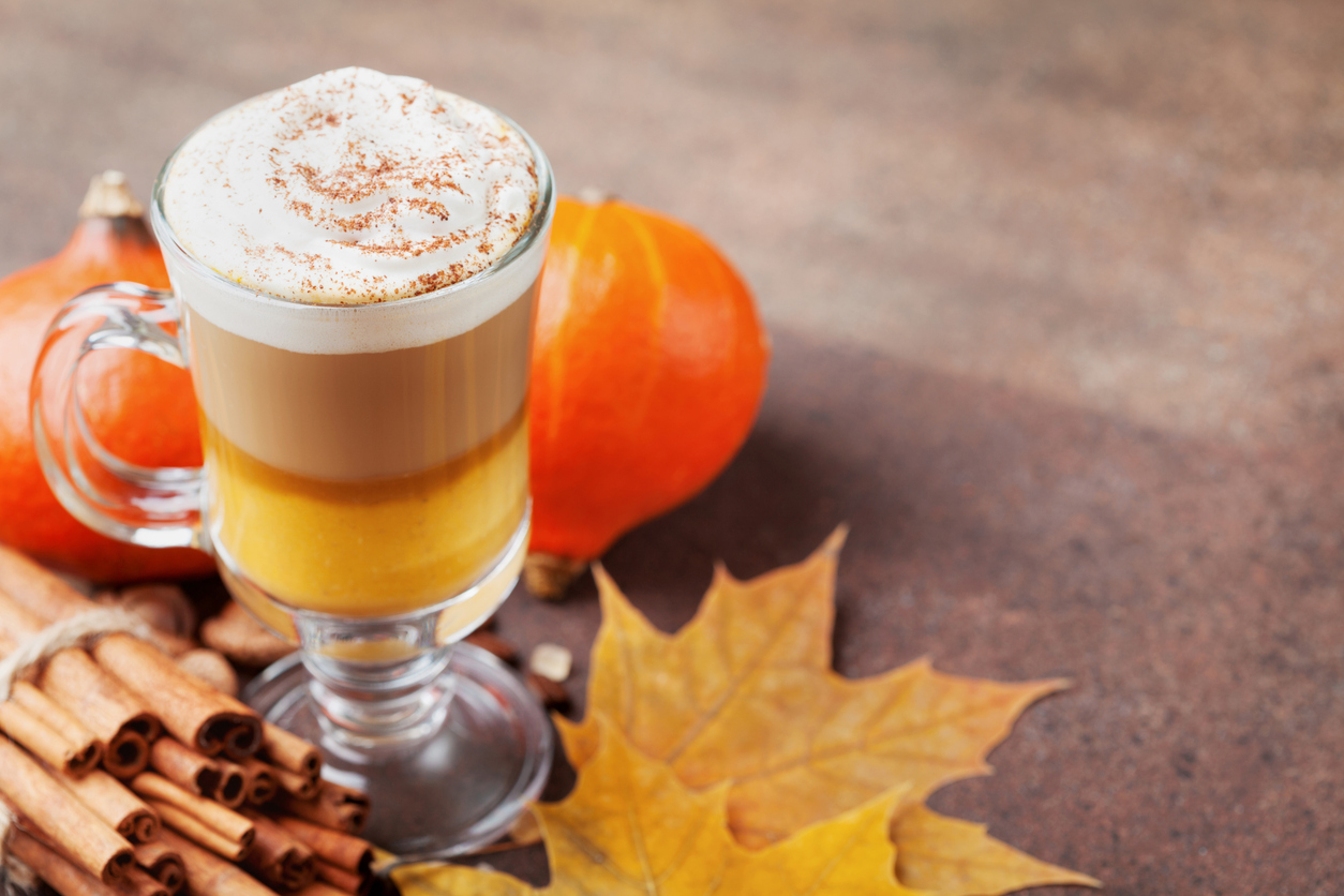 Latte Macchiato mit Kürbis, Milchschaum und Zimt in einer Glastasse.
