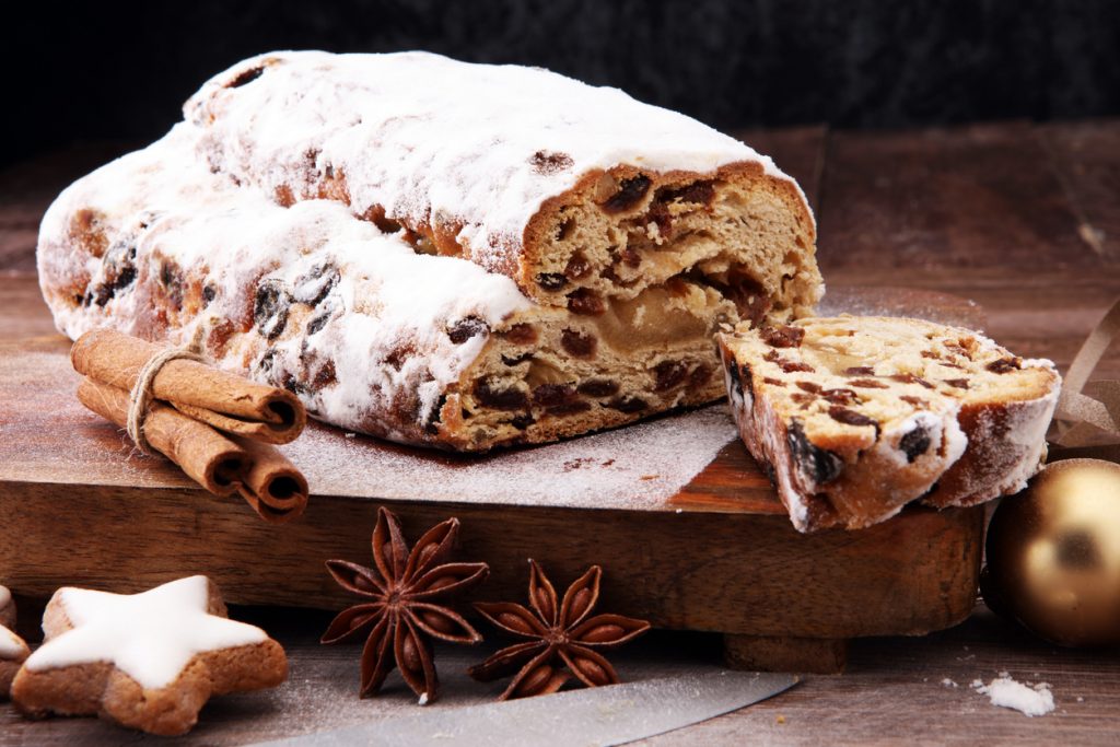 Ein Stollen mit herausgeschnittener Scheibe zeigt den hellen Marzipankern und viel Puderzucker.