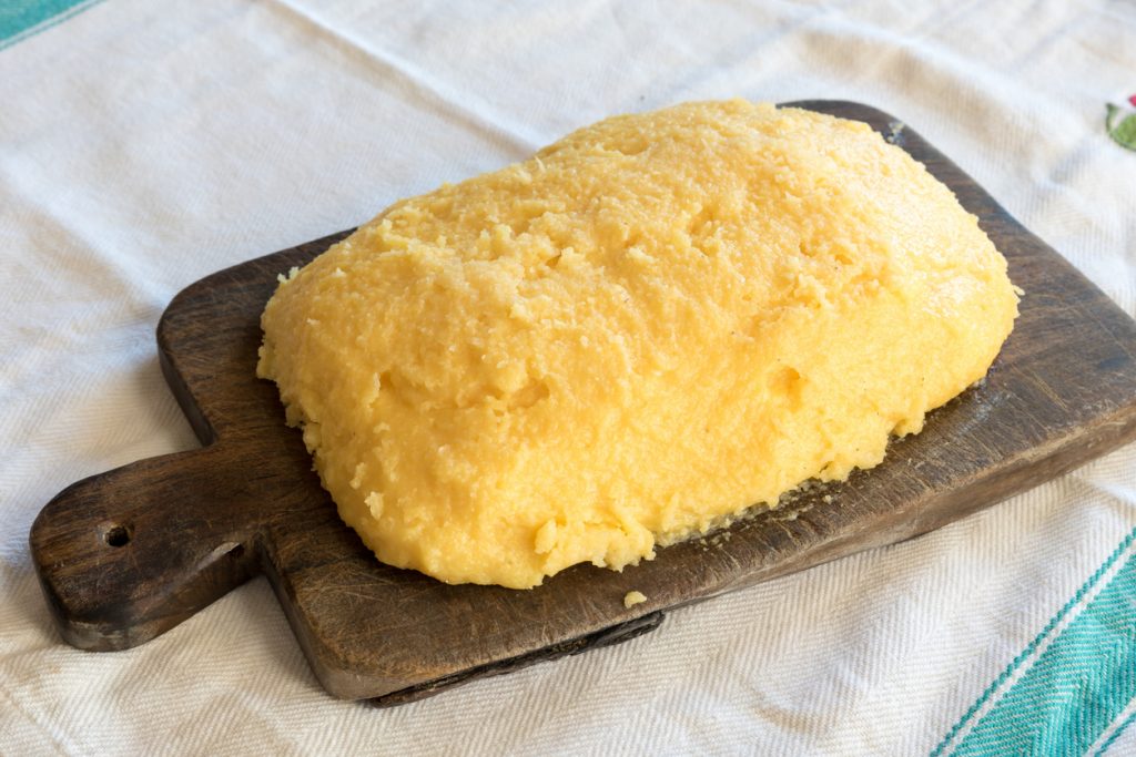 Noch warme Polentamasse auf rustikalem Holzbrett.