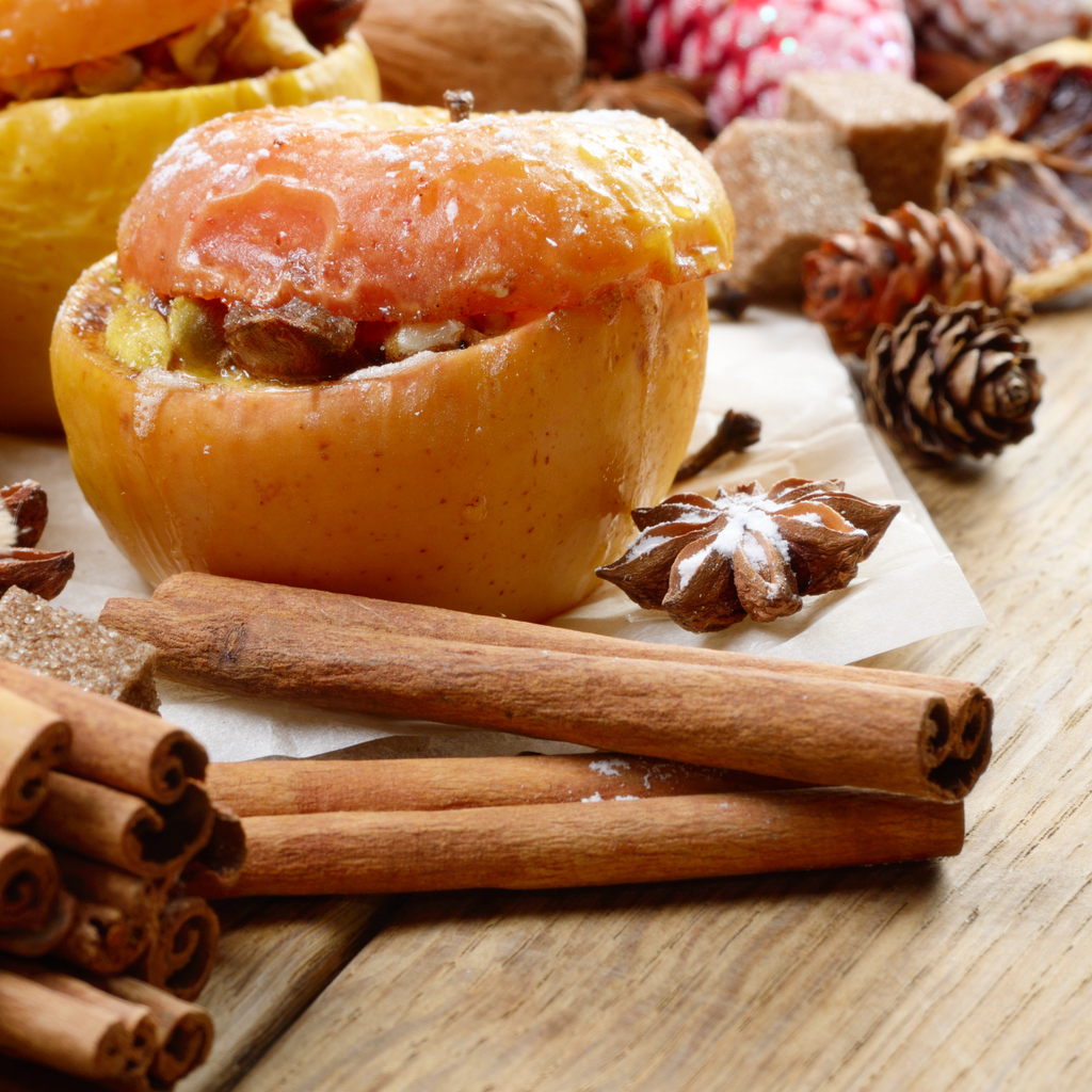 Gefüllter Apfel mit Zimtstangen und Sternanis auf Backpapier.