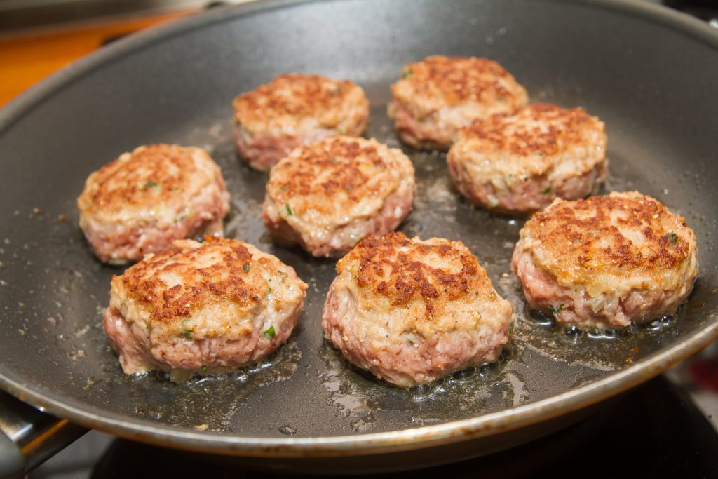In einer Pfanne braten acht Bouletten nebeneinander und bekommen eine knusprige Kruste.