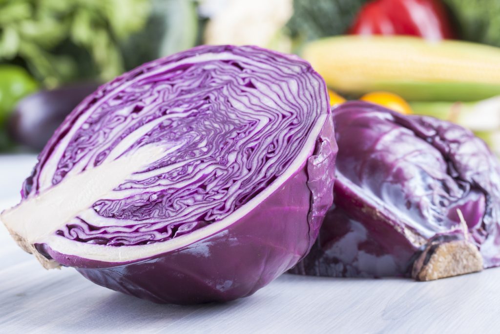 Ein halber Rotkohl liegt auf einer hellen Fläche und zeigt die feinen violett weißen Ringe im Inneren.