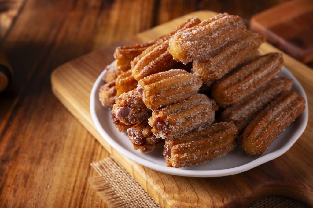 Zuckerummantelte Churros Stücke in einer Schale auf einem rustikalen Holztisch.