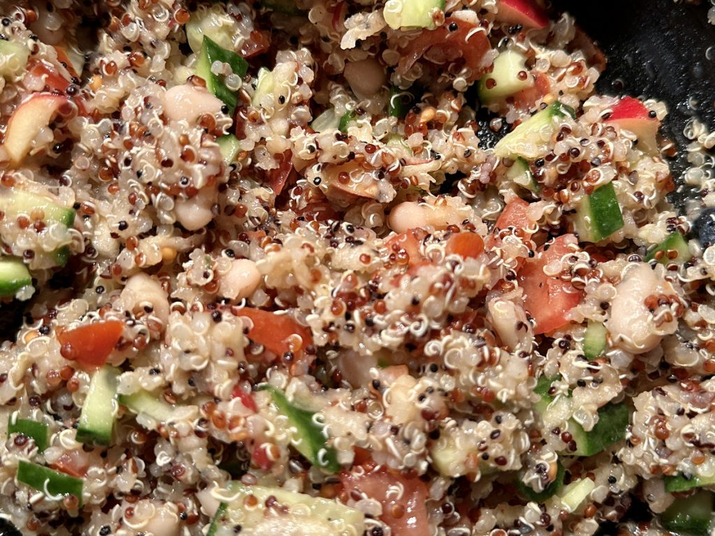 Ein Quinoa-Salat mit Gemüse ist sehr nah fotografiert und wirkt frisch und saftig.