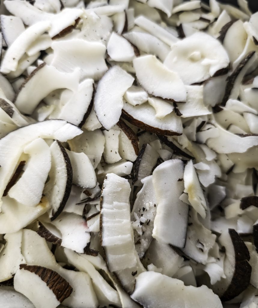 Viele dünne Kokoschips mit brauner Schale liegen dicht nebeneinander in einer Nahaufnahme.