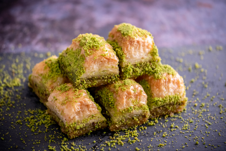 Mehrere Stücke Baklava sind zu einem kleinen Stapel auf dunklem Untergrund angeordnet.