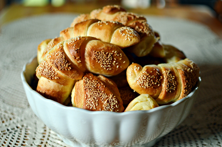 Mehrere Croissants mit Sesam garniert in einer weißen Keramikschüssel auf einer Spitzendecke.
