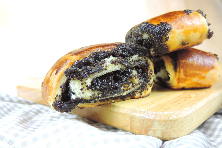 Mehrere saftige Mohnrollen sind auf einem Holzbrett übereinander angerichtet.