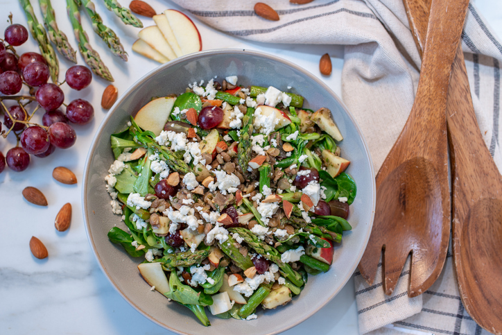 Von oben ist ein Grüner Spargelsalat mit Spargel, Blattsalat, Trauben, Apfel, Mandeln und Käse zu sehen.