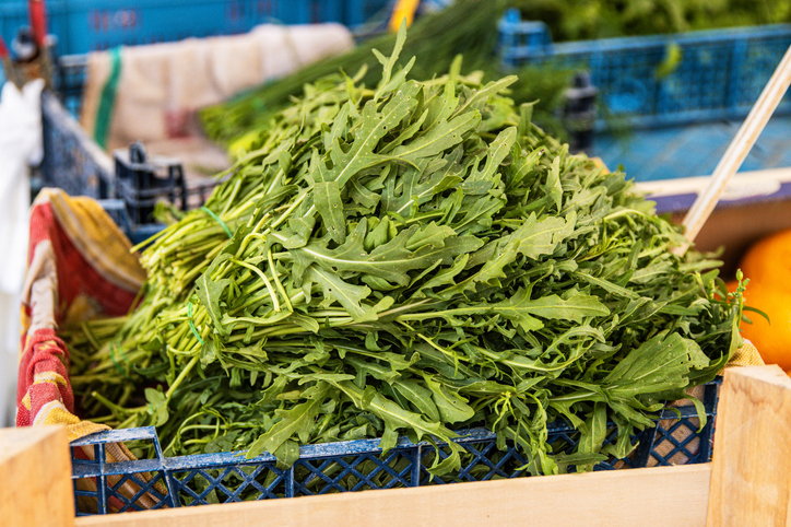 Eine Nahaufnahme von glänzenden, frischen Rucolablättern, die bereit für die Zubereitung sind.