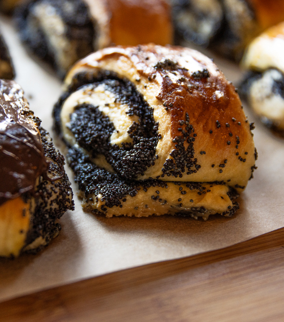 Eine einzelne saftige Mohnrolle mit sichtbarer Spiralform und reichlich Mohnfüllung ist nah zu sehen.