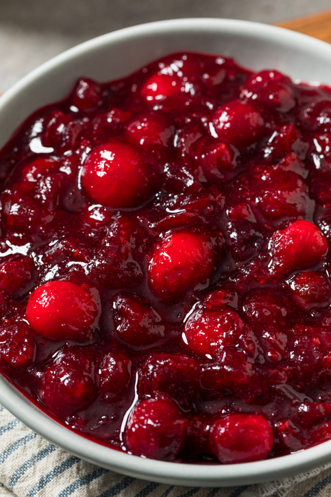 Die Nahaufnahme zeigt eine Schale mit dick eingekochter Cranberrysauce und ganzen roten Beeren.