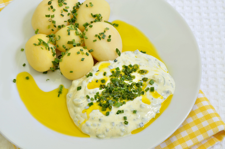 Draufsicht auf Pellkartoffeln mit Quark und Leinöl auf einem Teller, der auf einer gelb-weiß karierten Serviette steht.