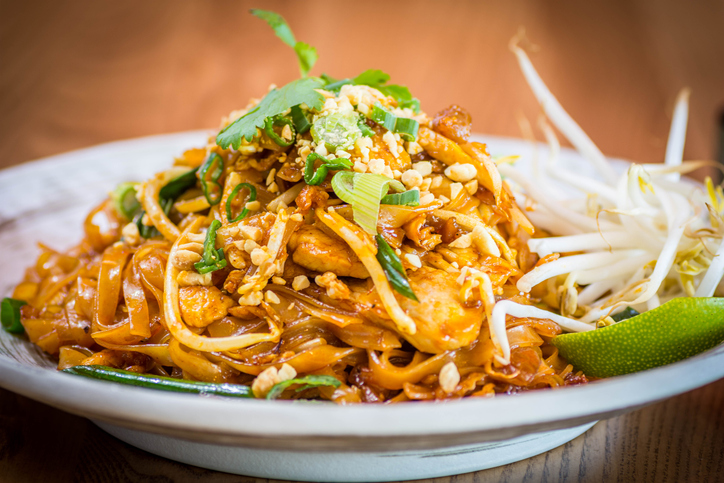 Ein herzhafter Teller Pad Thai mit Hähnchenfleisch, bestreut mit gehackten Erdnüssen, frischem Koriander und Sojasprossen