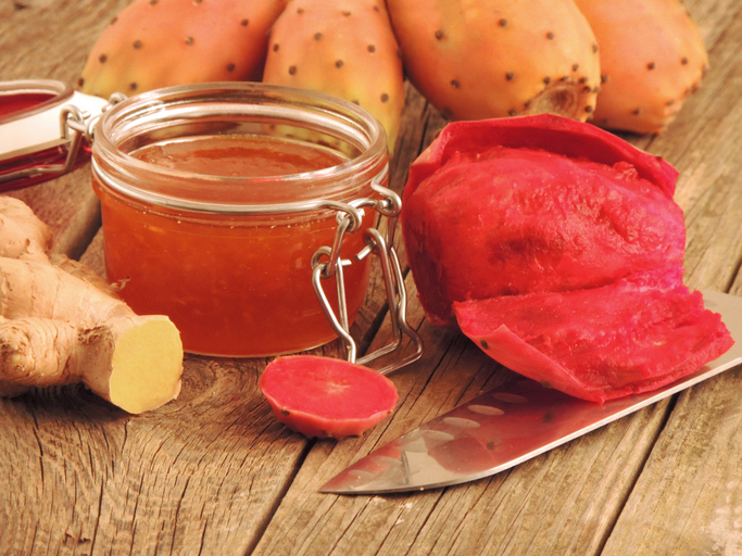 Glas mit Kaktusfeigenmarmelade neben Früchten, Fruchtfleisch und Ingwer