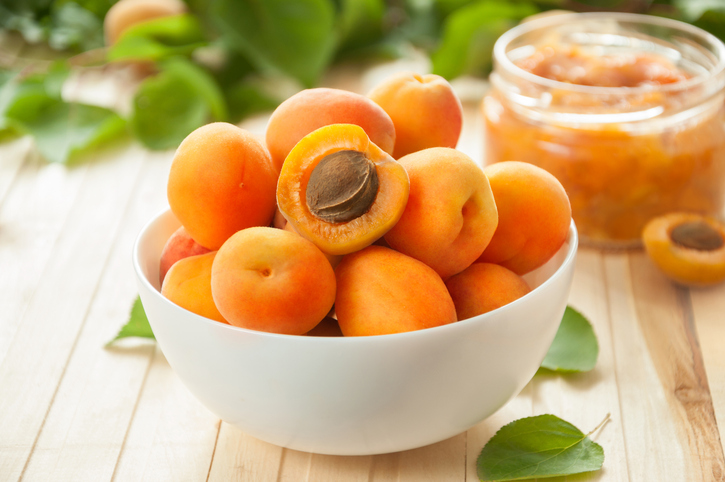 Schale mit reifen Aprikosen und Aprikosenmarmelade im Hintergrund