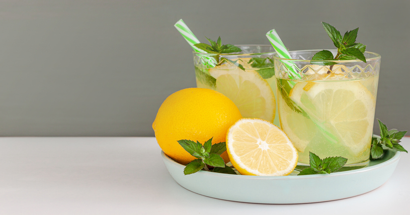 Zwei Gläser Detox-Sommerwasser mit Zitrone, Minze und Trinkhalmen