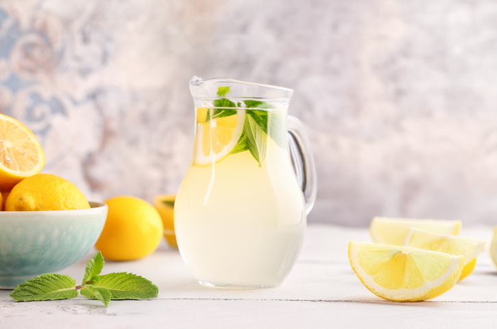 Karaffe mit Detox-Sommerwasser, Zitronenstücken und frischen Minzblättern