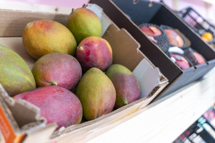 Mehrere Mangos in einem offenen Karton in einem Geschäft