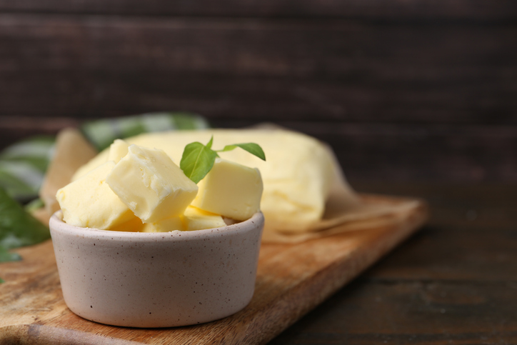 Kleine Stücke Butter liegen in einer hellen Schale auf einem Holzbrett.