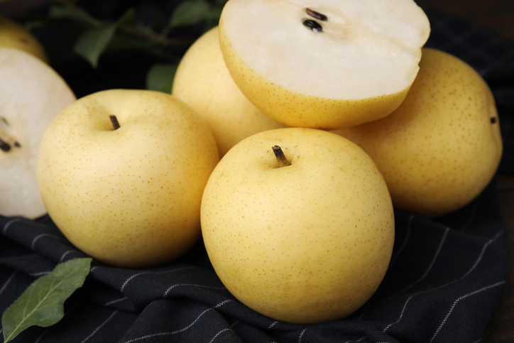 Mehrere Nashibirnen mit aufgeschnittener Frucht auf dunklem Untergrund