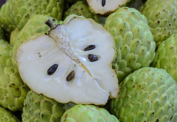 Halbierte Cherimoya mit weißem Fruchtfleisch und schwarzen Kernen