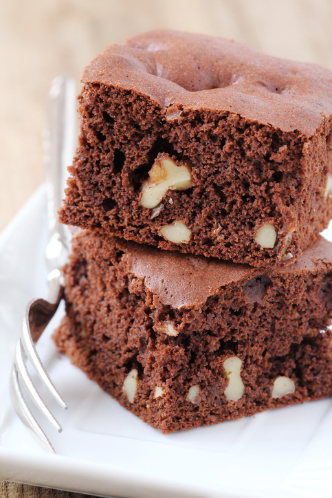 Zwei schokoladige Walnuss-Brownies mit sichtbaren Walnussstücken auf einem weißen Teller.
