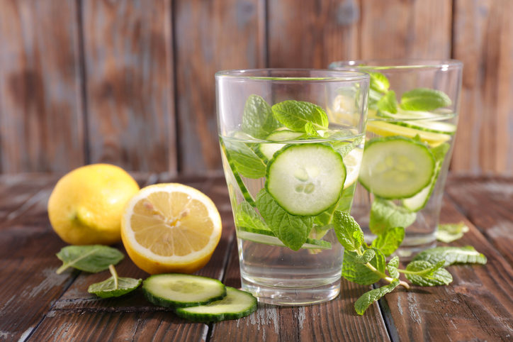 Gläser mit Detox-Sommerwasser, Gurkenscheiben, Zitrone und frischer Minze