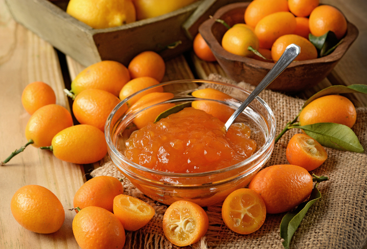 Kumquat-Marmelade in einer Glasschale mit frischen und halbierten Früchten