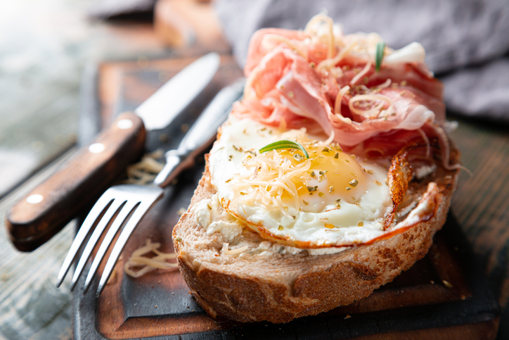 Strammer Max auf einer kräftigen Brotscheibe mit Spiegelei, Schinken, geriebenem Käse und frischen Kräutern.