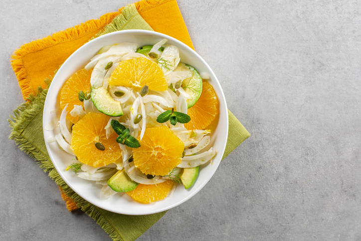 Fenchel-Orangen-Salat in einer weißen Schale mit Orangenscheiben, fein geschnittenem Fenchel, Avocado, Kürbiskernen und frischer Minze.