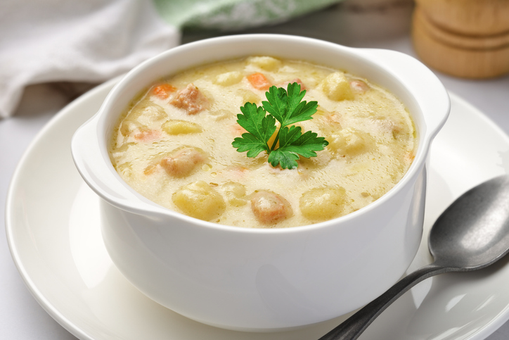 Kartoffelsuppe in einer weißen Suppenschüssel, garniert mit Petersilie und kleinen Einlagen aus Kartoffeln und Gemüse.