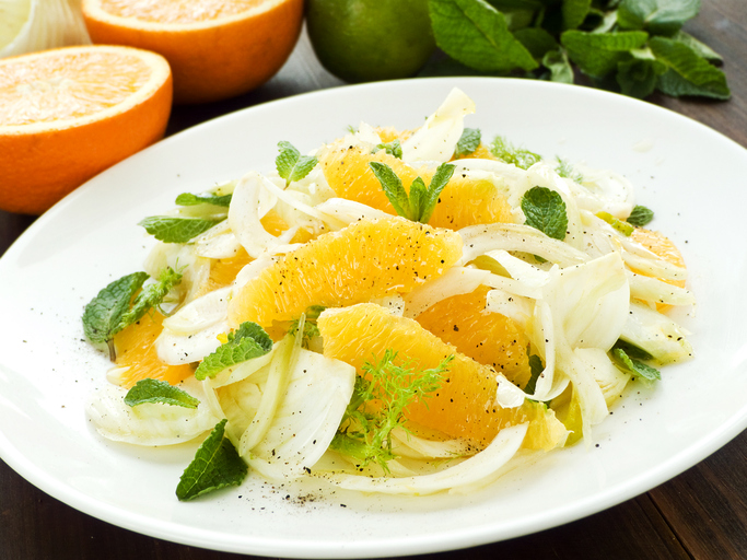 Fenchel-Orangen-Salat auf einem weißen Teller mit Orangenfilets, fein geschnittenem Fenchel, frischer Minze und schwarzem Pfeffer.