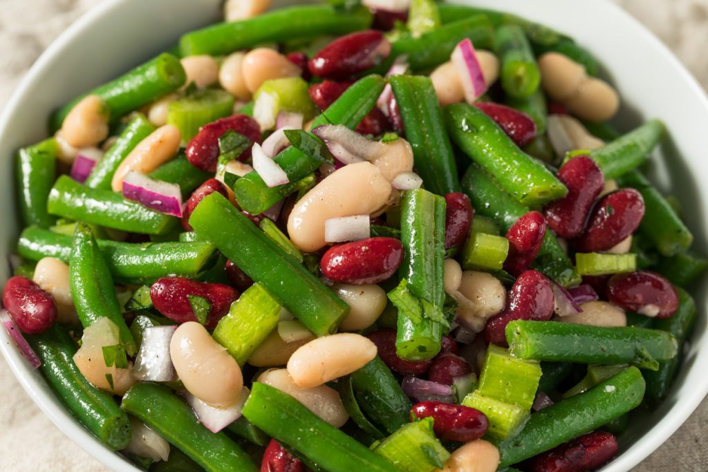 Nahaufnahme eines frischen Drei-Bohnen-Salats mit grünen Bohnen, Kidneybohnen, weißen Bohnen und roten Zwiebeln.