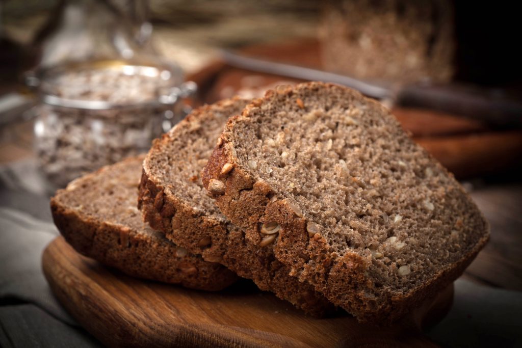 Nahaufnahme von geschnittenem Vollkornbrot mit Sonnenblumenkernen auf einem Holzbrett.