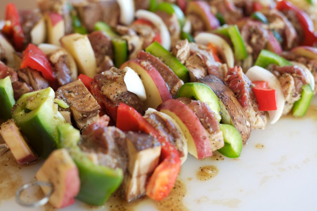 Marinierte Lammspieße mit buntem Gemüse wie Paprika, Zwiebeln und Pilzen, fertig zum Grillen.