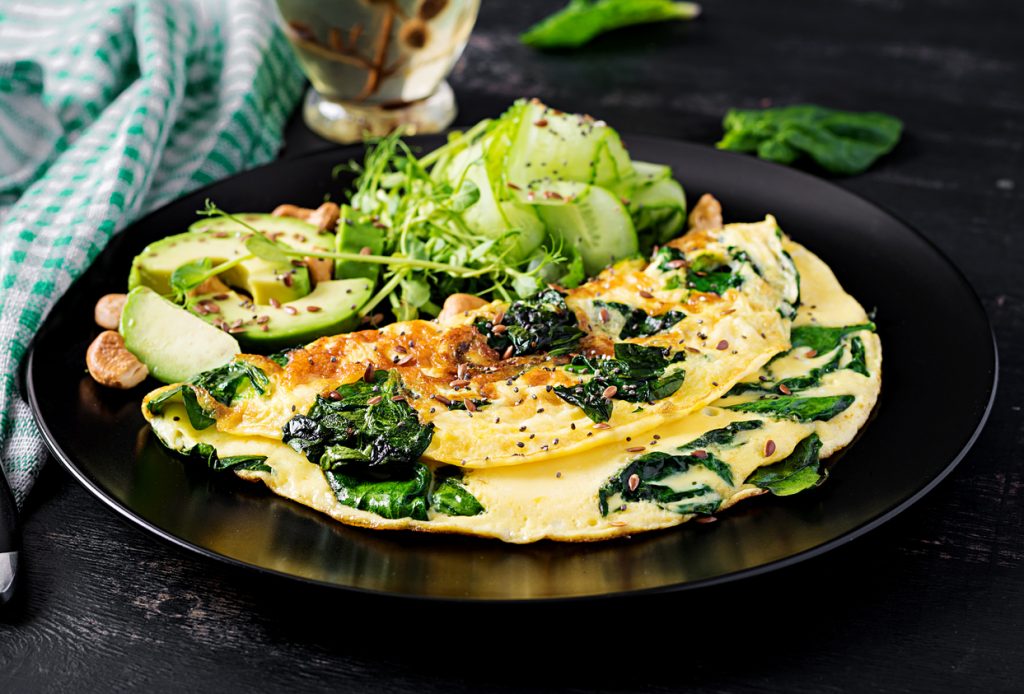 Omelett mit Spinat und Avocado neben grünem Salat