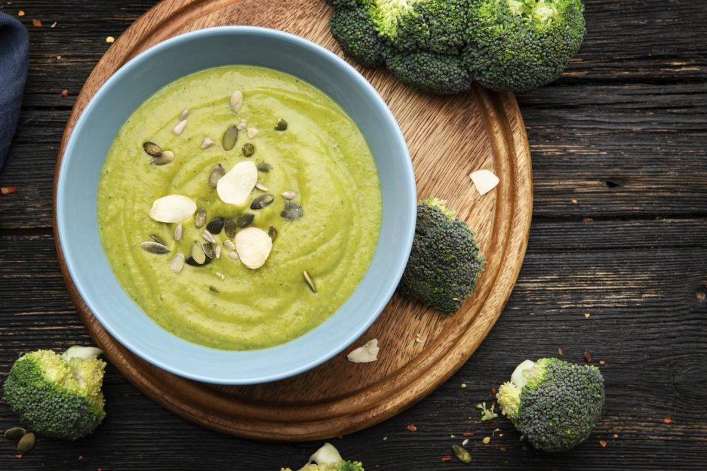 Blaue Schale Brokkolicremesuppe mit Kernen und Mandeln.