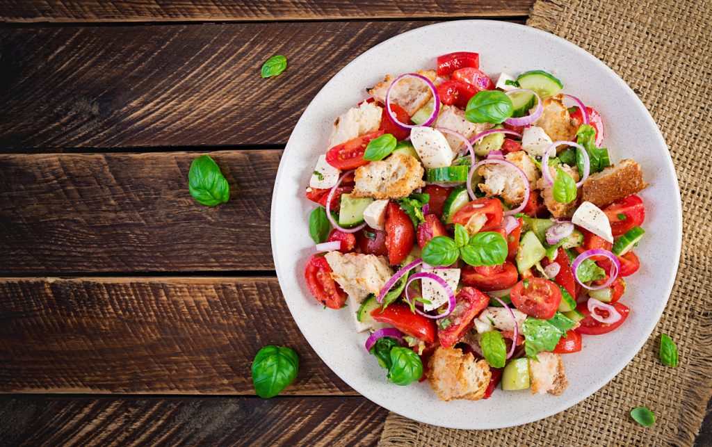 Teller mit toskanischem Panzanella-Brotsalat aus Tomaten, Gurke, roten Zwiebeln und Basilikum