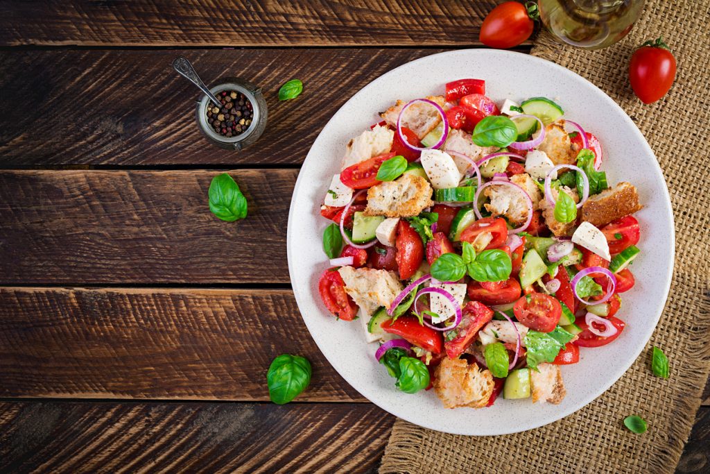 Teller mit toskanischem Panzanella-Brotsalat aus Tomaten, Gurken, Zwiebeln und Basilikum