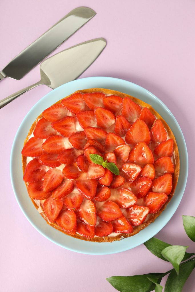 Frischer Erdbeerkuchen von oben auf einem Teller, glänzende Erdbeeren.