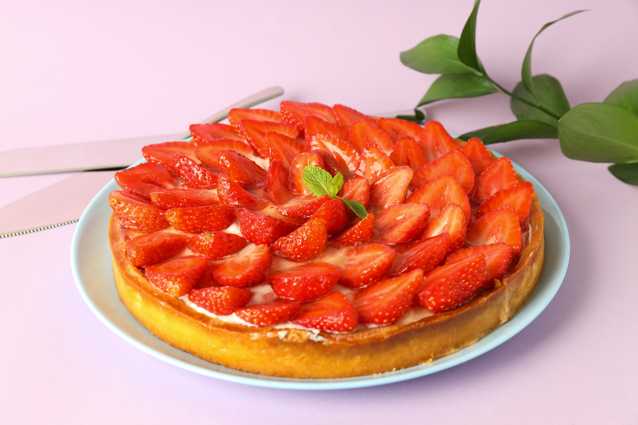 Erdbeerkuchen mit halbierten, glänzenden Erdbeeren auf Mascarponecreme, serviert auf Teller.