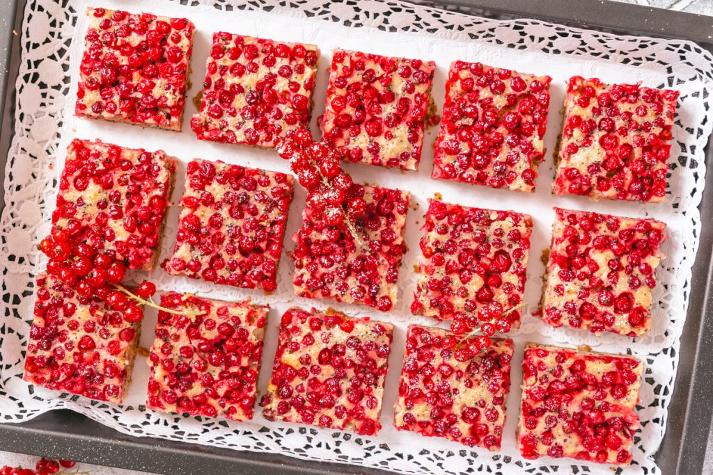 Johannisbeer-Blechkuchen mit Mohn, in gleichmäßige Stücke geschnitten und mit frischen Johannisbeeren dekoriert.