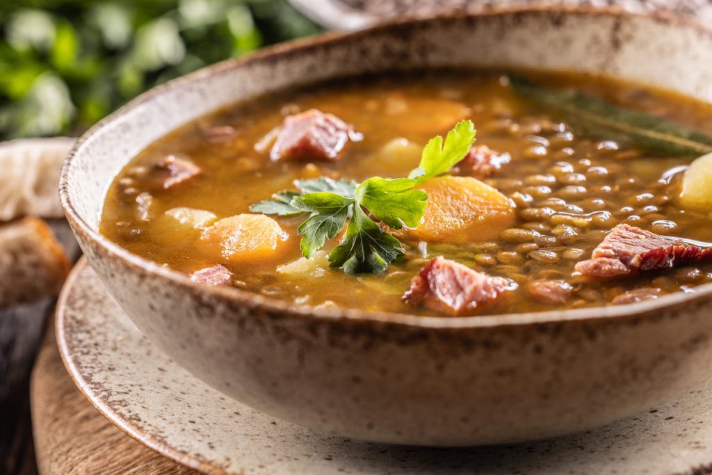Linsensuppe mit Gemüse und Speck in rustikaler Schüssel