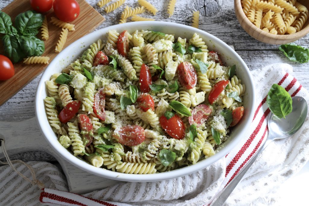Schüssel mit Pesto-Fusilli, Tomaten, Käsewürfeln und Basilikum
