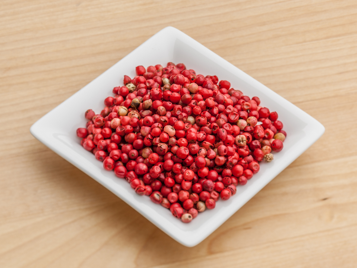 Weiße Schale mit roten Pfefferbeeren auf Holz