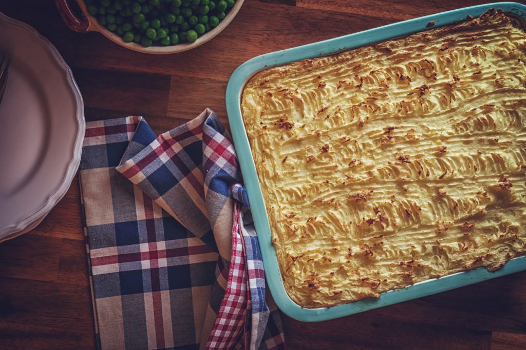 Obere Ansicht einer rechteckigen Auflaufform mit Shepherd’s Pie und goldbraun geriffelter Kartoffelpüreehaube.